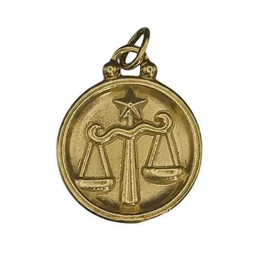 close-up of gold round charm with Libra scales and star