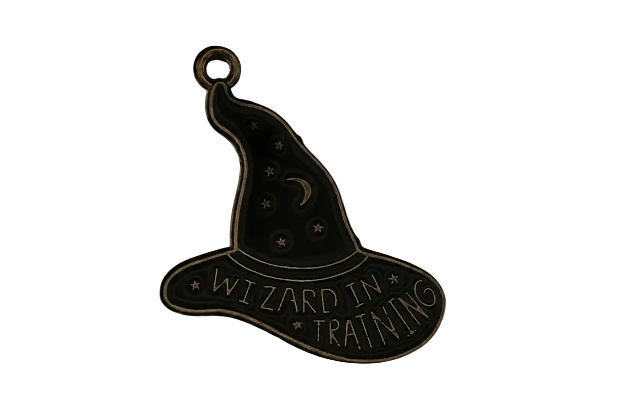 close-up of antique gold wizard hat charm with moon, stars, and the words "WIZARD IN TRAINING"