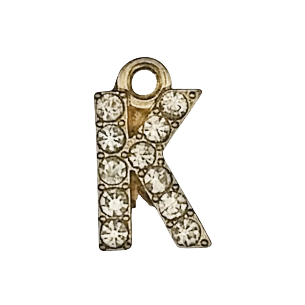 close-up of gold-tone letter K charm with clear crystals on black background