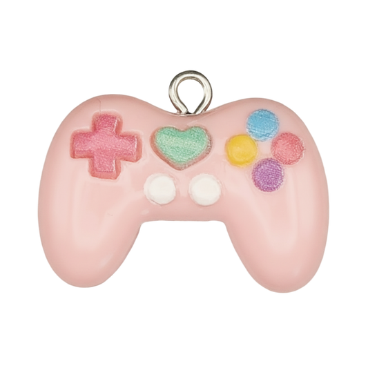 close-up of a pink game controller charm with multicolor buttons on a black background