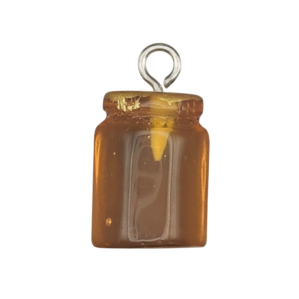 close-up of a miniature honey jar charm with amber fill on a black background