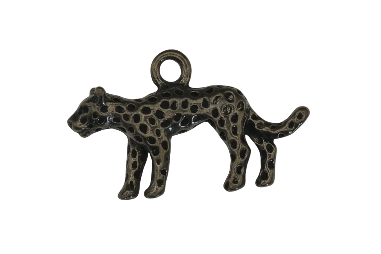 close-up of a small metal leopard charm with raised spots on a black background