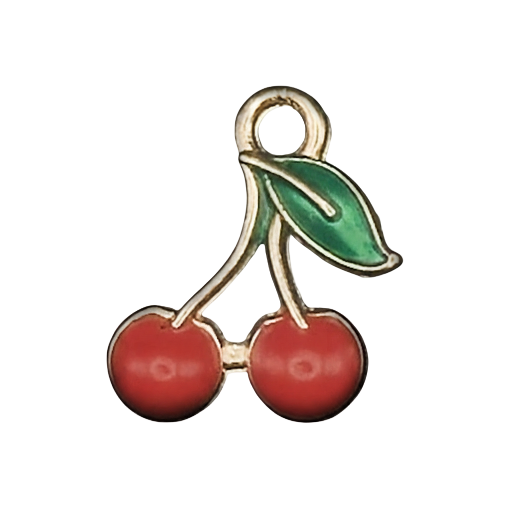close-up of a small gold-tone cherry charm with red cherries and a green leaf on a black background
