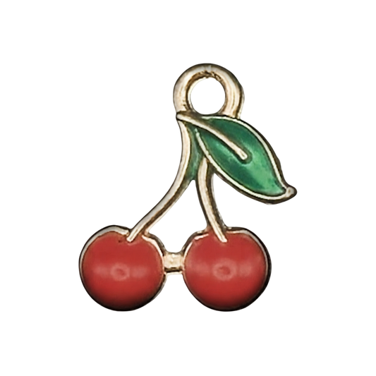 close-up of a small gold-tone cherry charm with red cherries and a green leaf on a black background