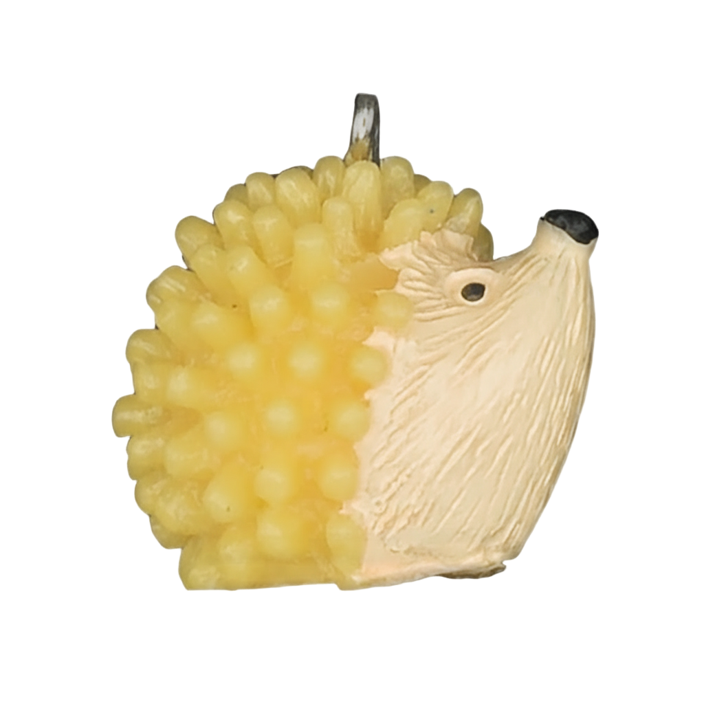 close-up of yellow and cream hedgehog charm on black background