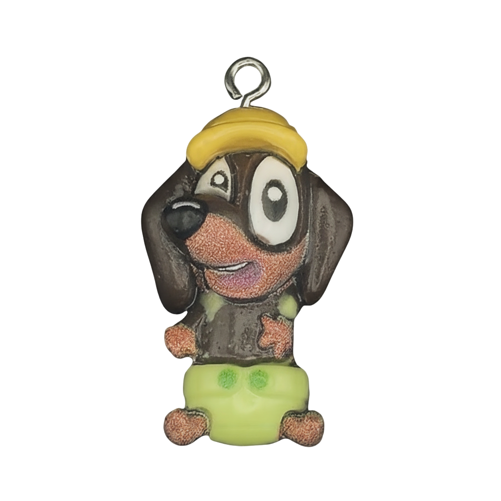 close-up of cartoon dog charm with yellow cap and green shorts on black background