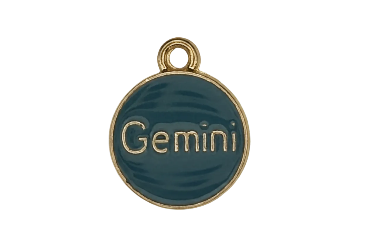 Close-up of round teal 'Gemini' enamel charm with gold-tone rim on a black background.