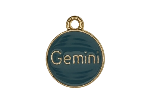 Close-up of round teal 'Gemini' enamel charm with gold-tone rim on a black background.