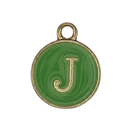 Close-up of a small round green charm with a gold letter J and rim on a black background.