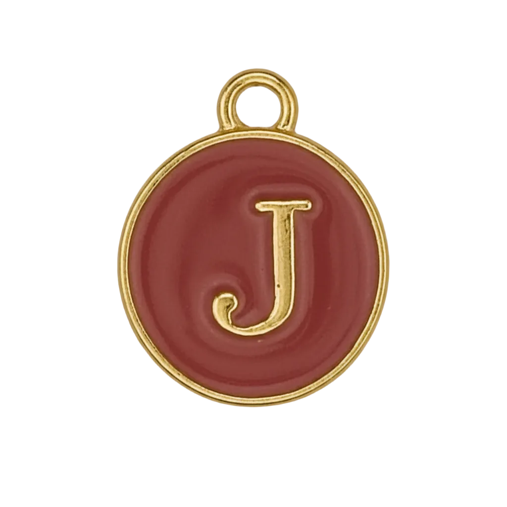 Round red charm with gold letter J on black background, close-up.