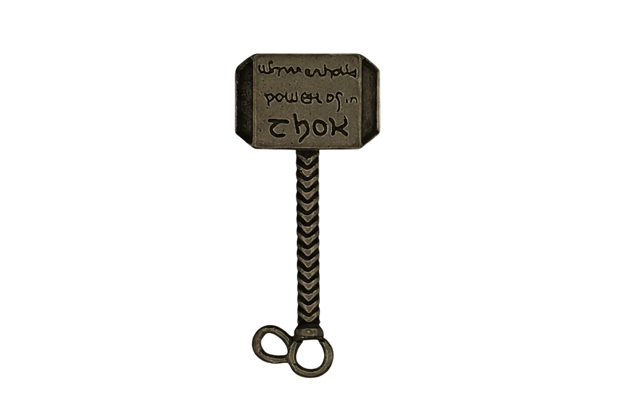 close-up of an antique brass hammer-shaped charm with engraved head on a black background