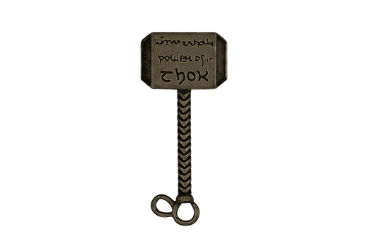 close-up of an antique brass hammer-shaped charm with engraved head on a black background