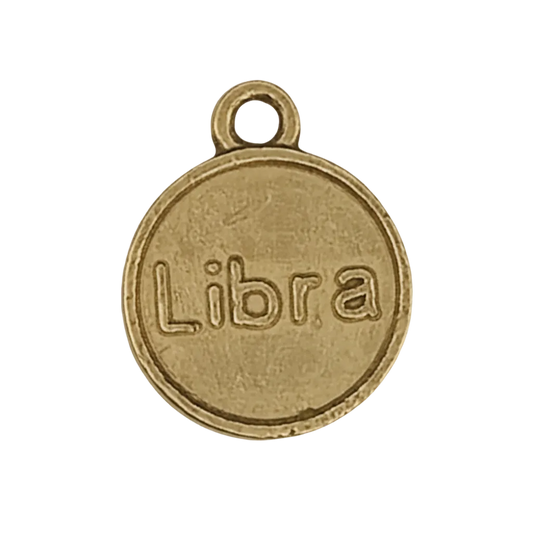 close-up of round gold-tone charm engraved with the word Libra