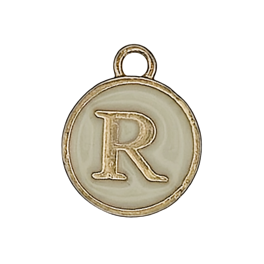 close-up of round gold-tone charm with letter R on a cream background