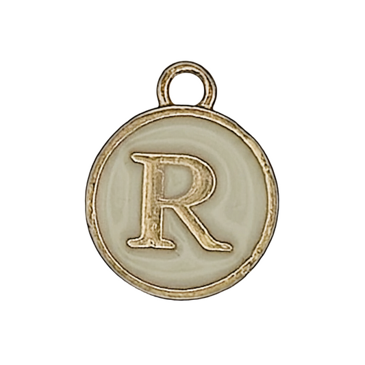 close-up of round gold-tone charm with letter R on a cream background