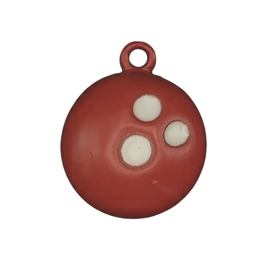 Close-up of red bowling ball charm with three white finger holes.