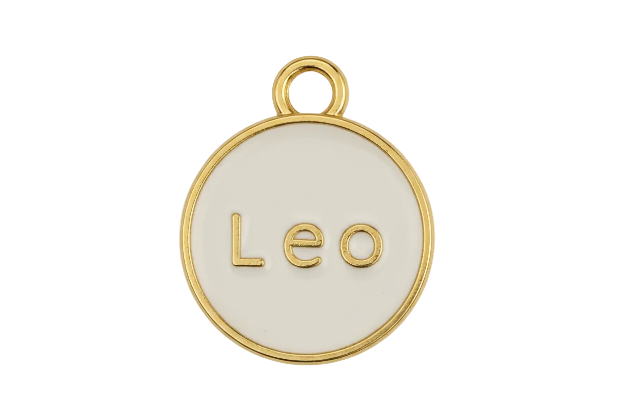 Close-up of round gold and cream 'Leo' disc charm on black background.