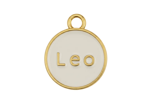 Close-up of round gold and cream 'Leo' disc charm on black background.