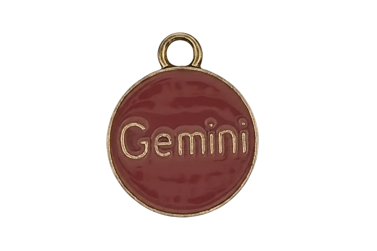 close-up of round red enamel charm with 'Gemini' text and gold-tone edge
