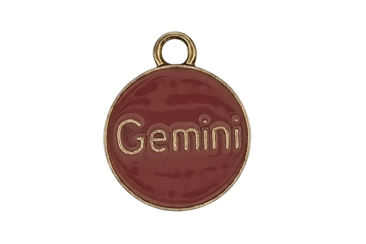 close-up of round red enamel charm with 'Gemini' text and gold-tone edge