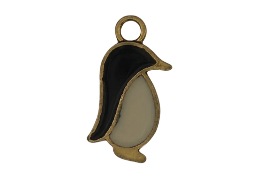 close-up of a small black and white penguin charm with gold outline on a black background