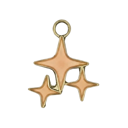 close-up of a gold-tone charm with three peach enamel starbursts on a black background
