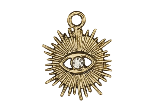 close-up of gold-tone sunburst eye charm with clear center stone on black background