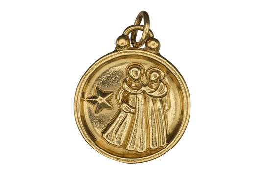 close-up of round gold-tone charm with two robed figures and a star on a black background