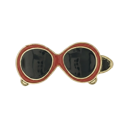 close-up of red sunglasses enamel charm with black lenses and gold outline on a black background