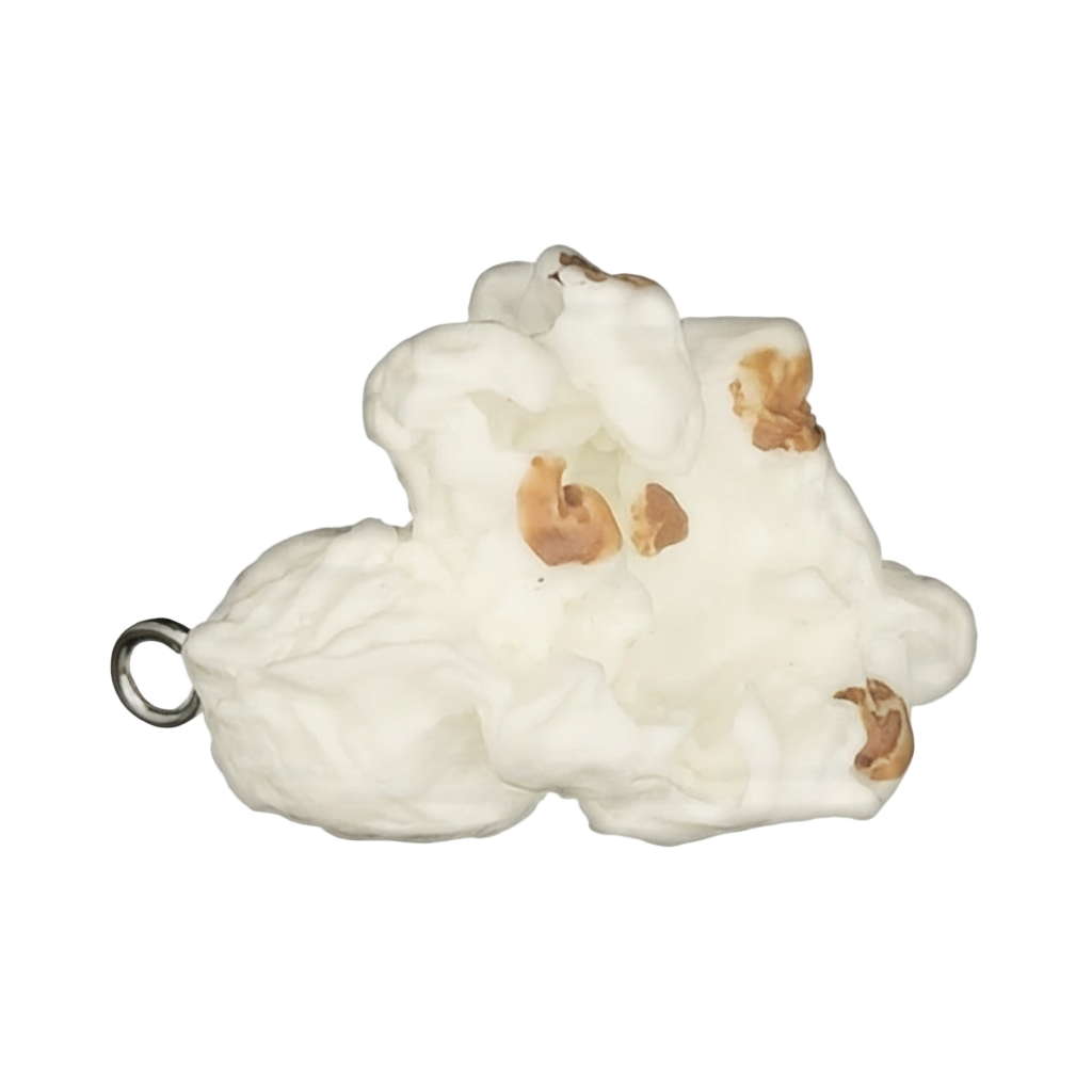 Close-up of a miniature popcorn charm with white puffs and brown spots on a black background.