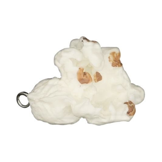 Close-up of a miniature popcorn charm with white puffs and brown spots on a black background.