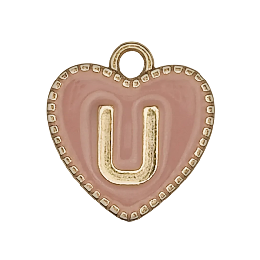 close-up of a pink heart charm with a raised gold letter U