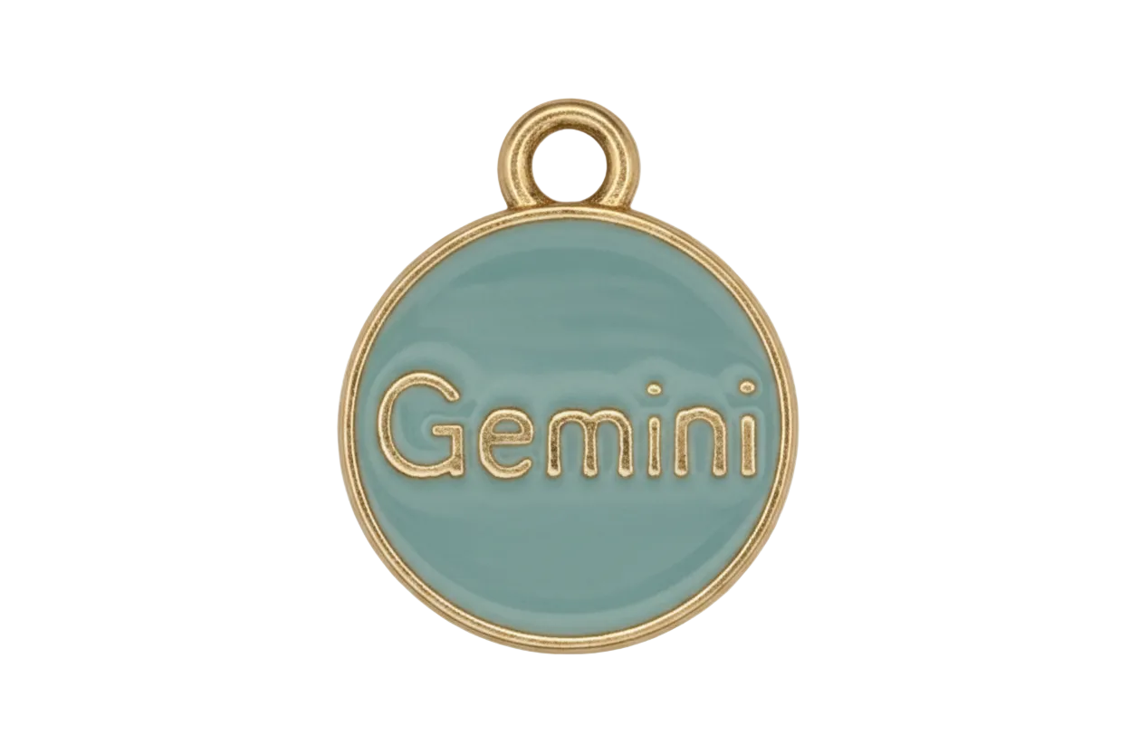 close-up of round light blue enamel charm reading Gemini with gold edge on black background