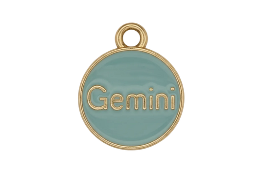 close-up of round light blue enamel charm reading Gemini with gold edge on black background