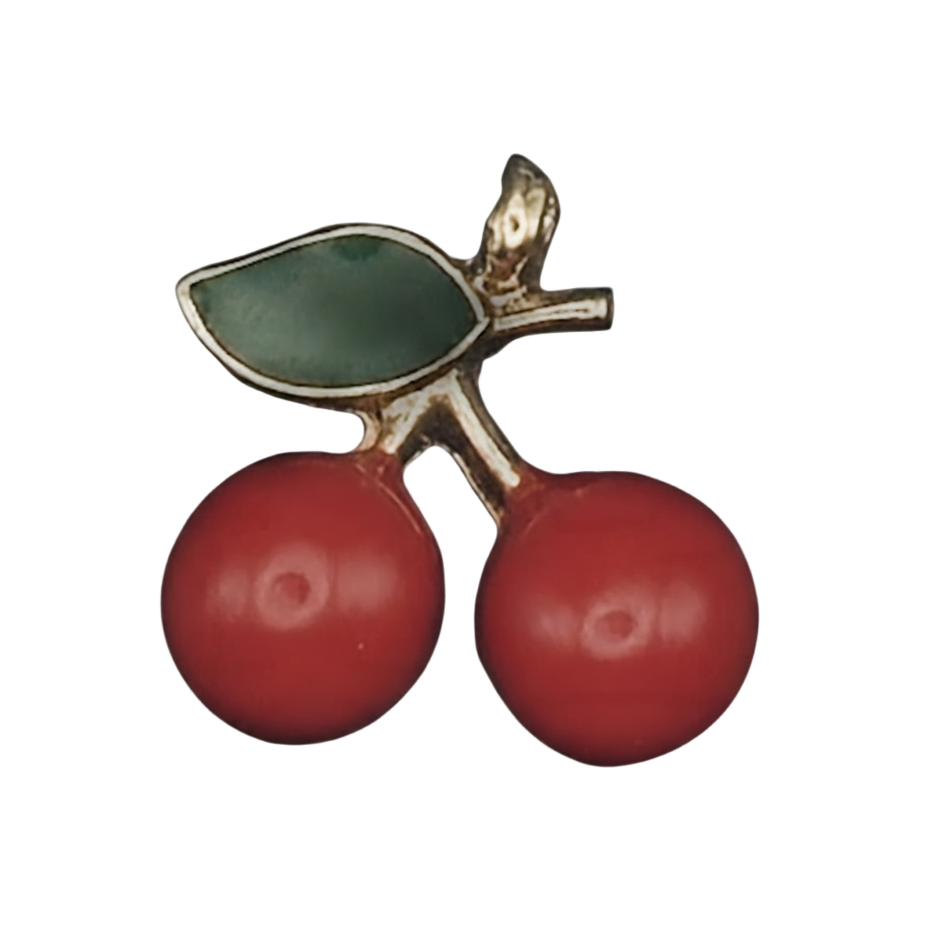 close-up of a small cherry charm with two red cherries and a green leaf outlined in gold on a black background