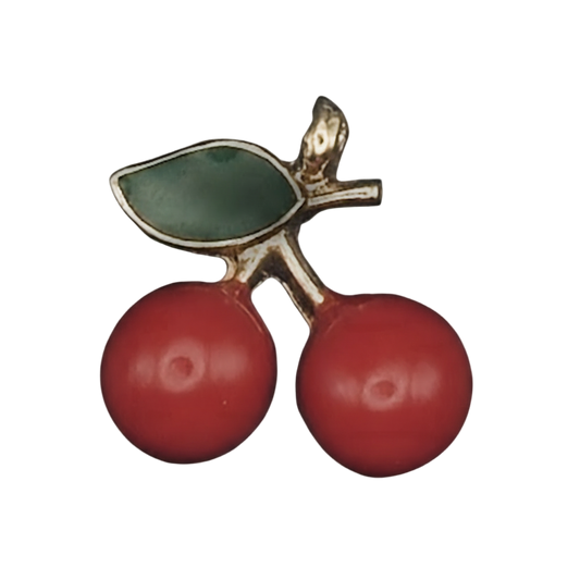 close-up of a small cherry charm with two red cherries and a green leaf outlined in gold on a black background