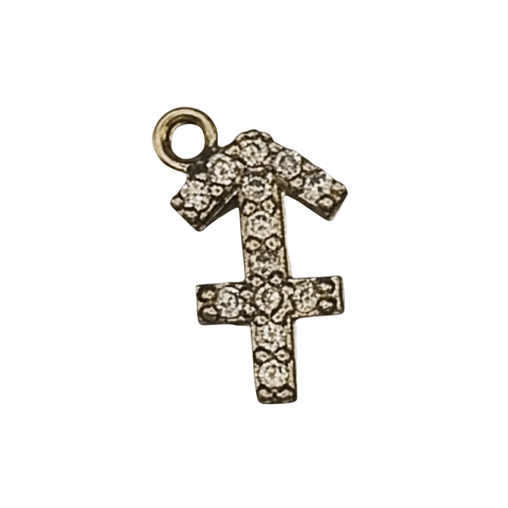 close-up of a gold-tone pavé Sagittarius symbol charm on a black background