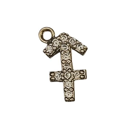 close-up of a gold-tone pavé Sagittarius symbol charm on a black background