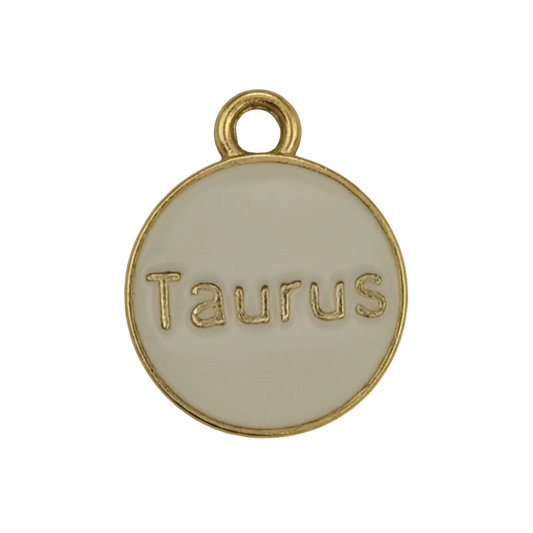 Close-up of a round gold-tone disc charm engraved “Taurus”.