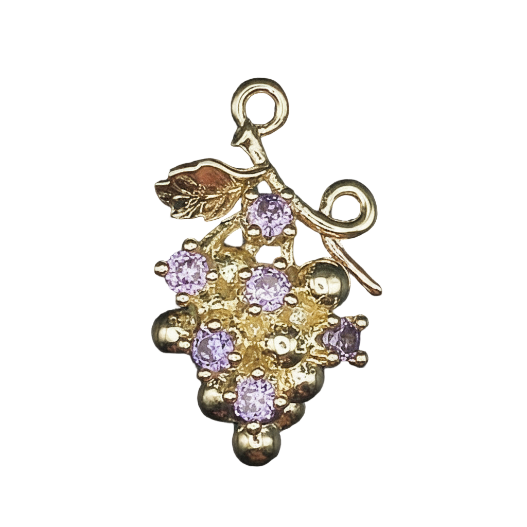 Close-up of gold-tone grape cluster charm with purple stones on black background.