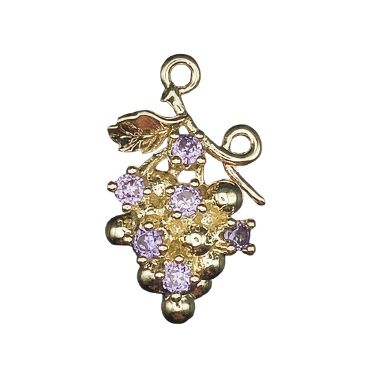 Close-up of gold-tone grape cluster charm with purple stones on black background.