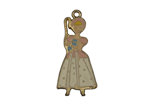 gold-tone enamel charm of a shepherdess with bonnet and crook in a pink and white dress on a black background