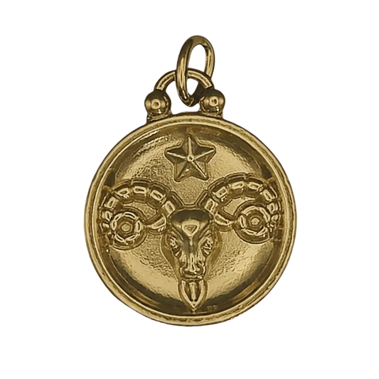 close-up of a gold round charm with a ram head and star motif on a black background