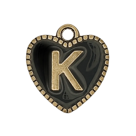 close-up of a black heart-shaped charm with a raised gold letter K and dotted gold border