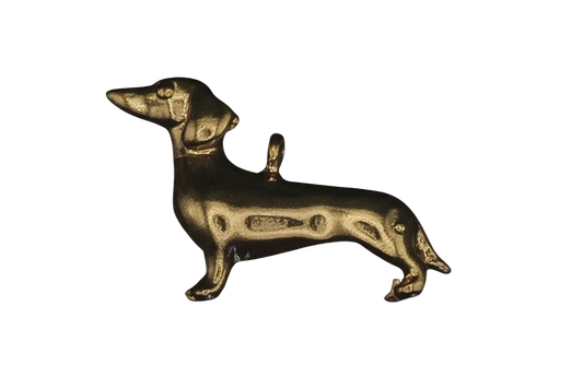 close-up of a gold dachshund dog charm on a black background