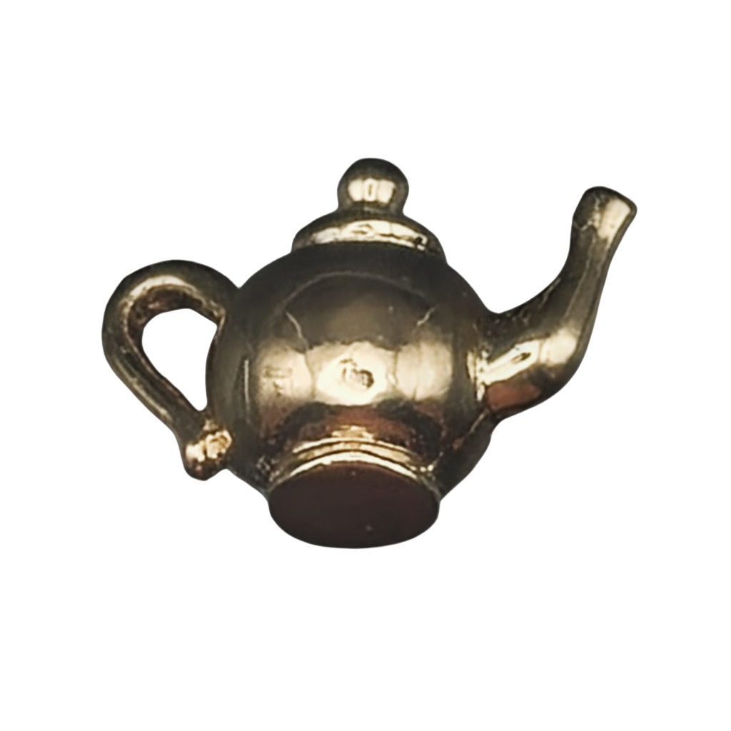close-up of small gold teapot charm on black background