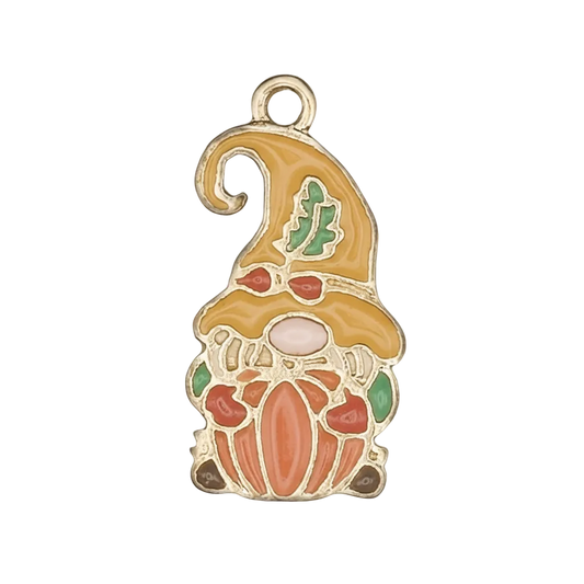 Close-up of gold-tone enamel gnome holding a pumpkin charm with yellow hat and green leaf on black background.