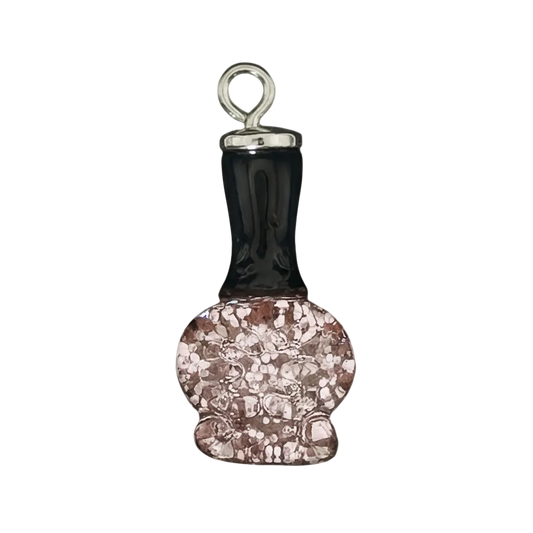 close-up of a nail polish bottle charm with a black cap and pink glitter bottle on a black background