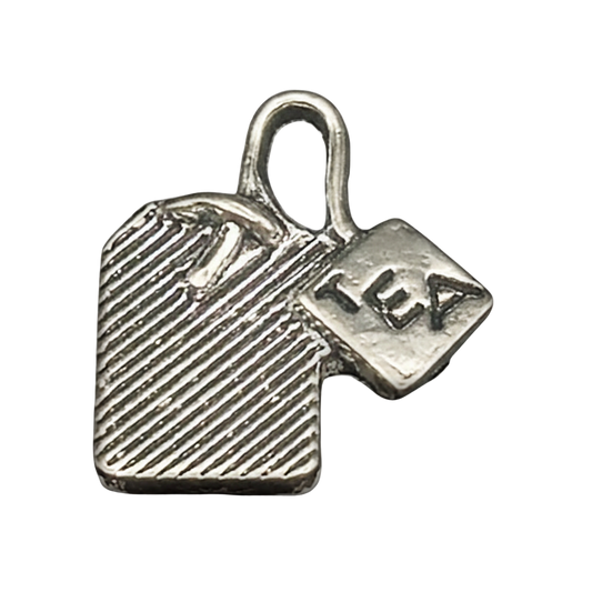Close-up of a silver tea bag charm with a tag reading "TEA" on a black background.