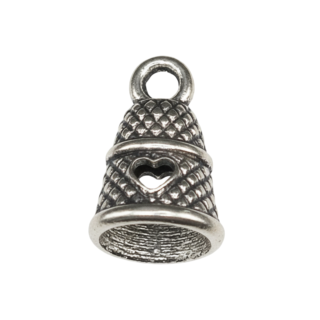 close-up of silver thimble charm with heart detail on black background